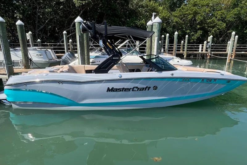 Slide: The Image of 2025 MasterCraft X24 boat docked in a marina, featuring sleek design and modern amenities. - 0