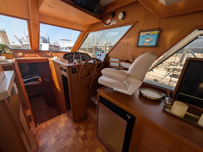 Slide: The Image of 1986 Ocean Alexander 39 Sedan interior with helm, wooden finish, and marina view. - 18