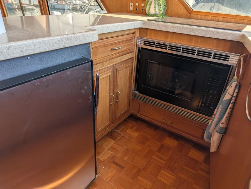 Slide: The Image of 1986 Ocean Alexander 39 Sedan kitchen with microwave, mini-fridge, and wooden cabinetry. - 26