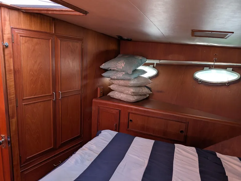 Slide: The Image of 1986 Ocean Alexander 39 Sedan cabin with wood paneling, striped bedding, and porthole windows. - 33