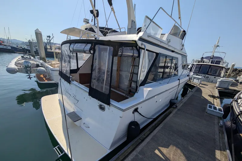 Slide: The Image of 1986 Ocean Alexander 39 Sedan yacht docked at marina, featuring enclosed deck and sleek design. - 5