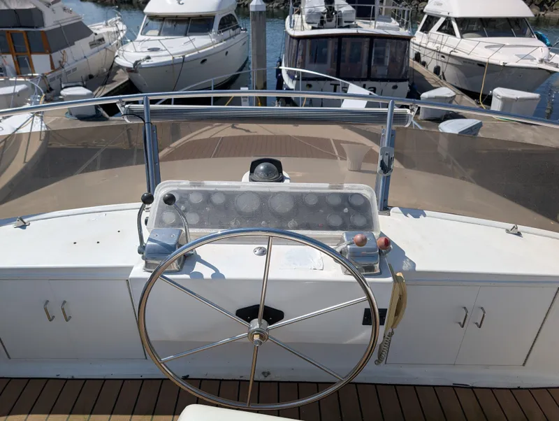 Slide: The Image of 1986 Ocean Alexander 39 Sedan helm with steering wheel, docked among other boats. - 50