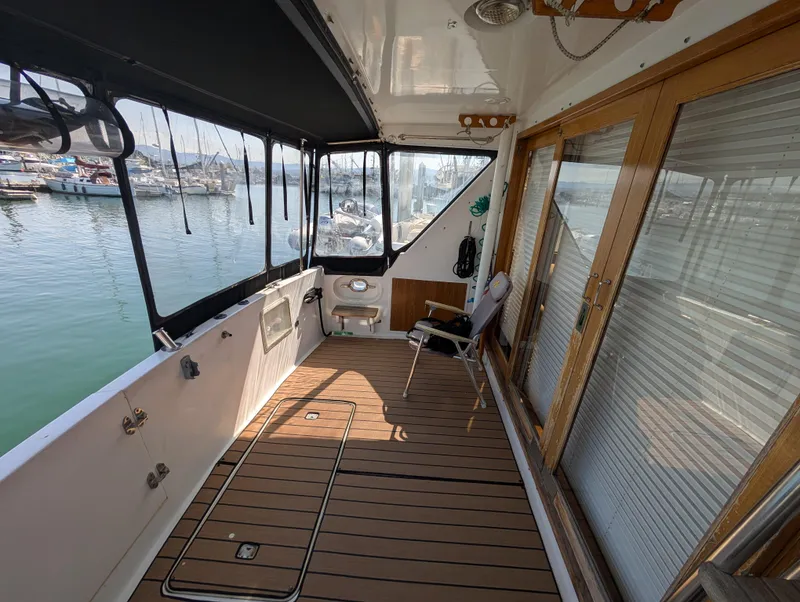 Slide: The Image of 1986 Ocean Alexander 39 Sedan yacht deck with wooden flooring and marina view. - 8