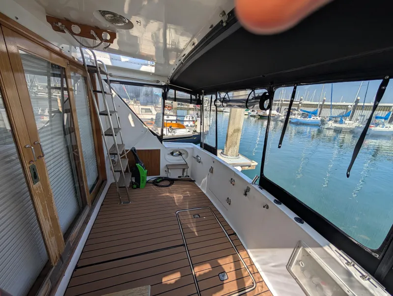 Slide: The Image of 1986 Ocean Alexander 39 Sedan yacht deck with wooden flooring and marina view. - 9