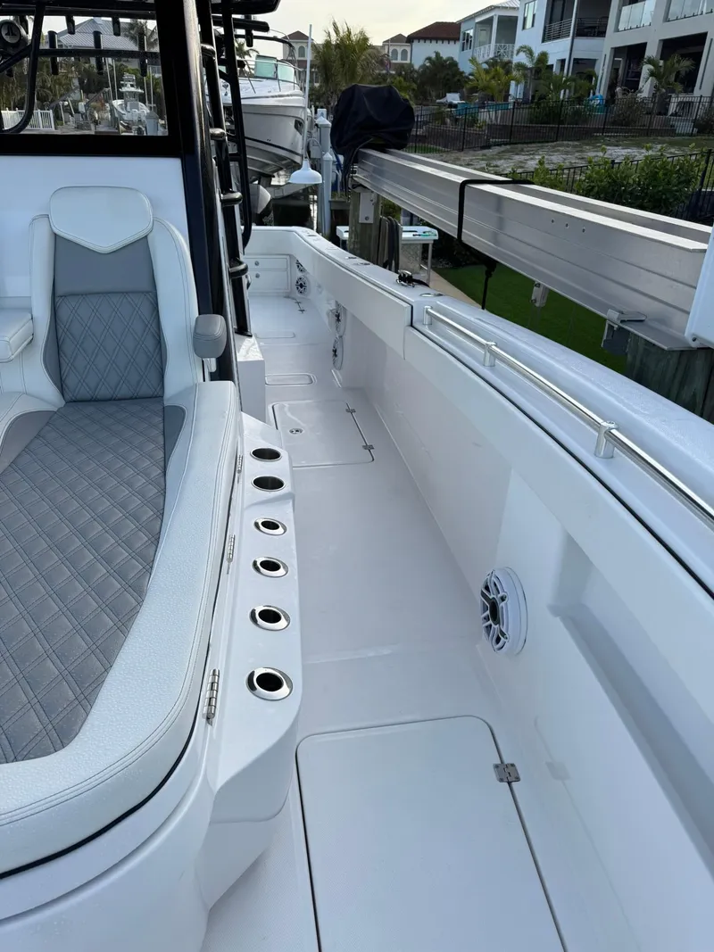 Slide: The Image of 2023 Invincible 33 Catamaran deck with seating and rod holders, docked near waterfront homes. - 10