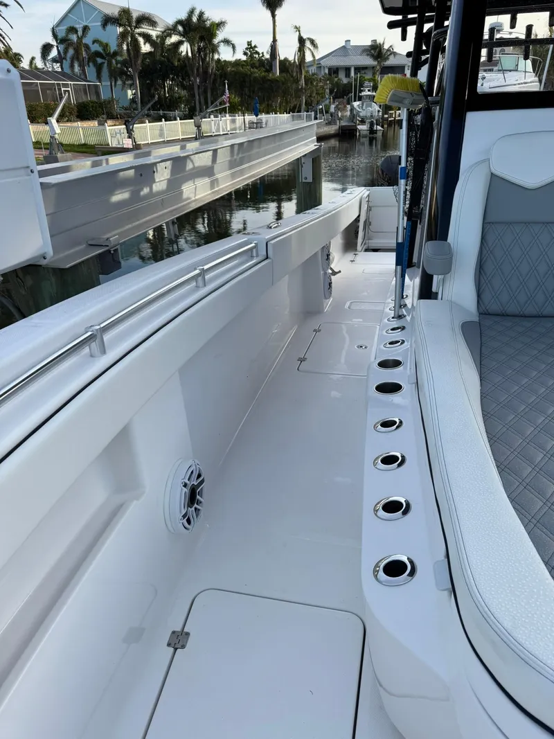 Slide: The Image of 2023 Invincible 33 Catamaran boat interior with seating and rod holders, docked by a canal. - 11