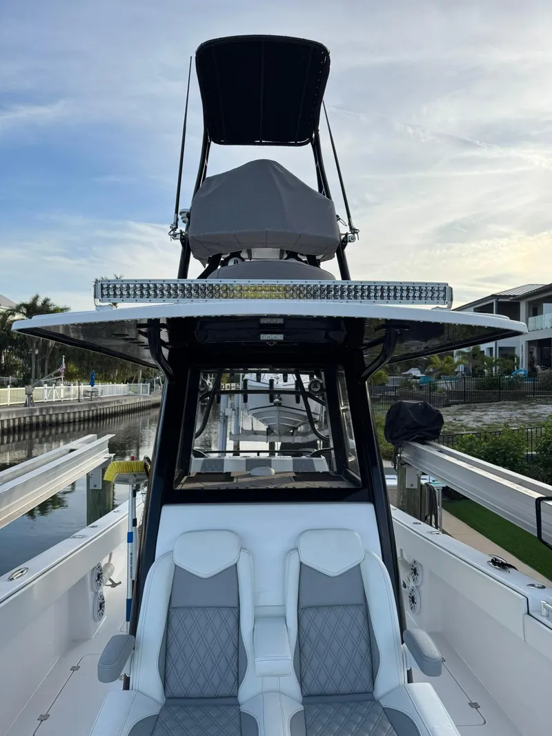 Slide: The Image of 2023 Invincible 33 Catamaran with dual seating and elevated helm station, docked by waterfront homes. - 12