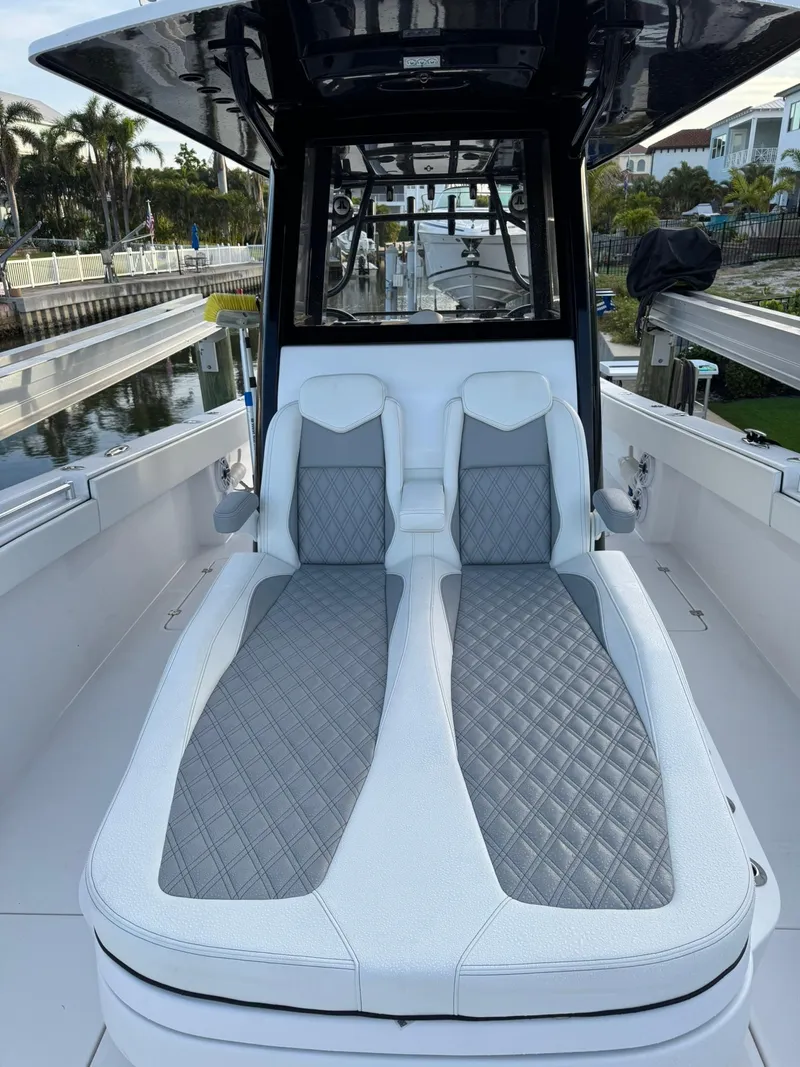 Slide: The Image of 2023 Invincible 33 Catamaran with luxurious seating and sleek design in a marina setting. - 9