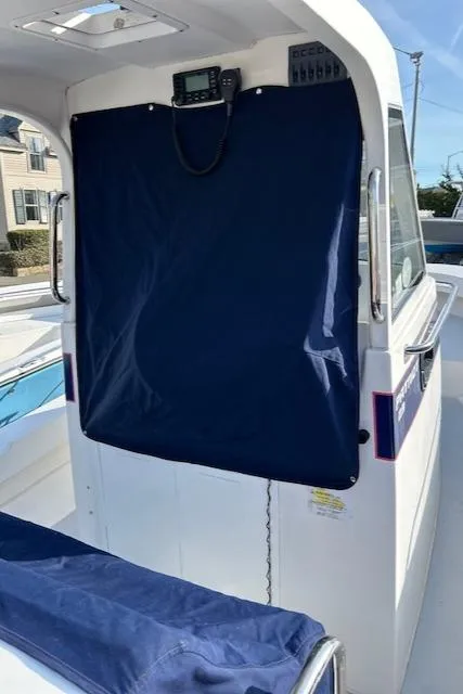 Slide: The Image of 2015 Maritime Skiff 23 Patriot boat with blue canvas cover and visible control panel. - 18