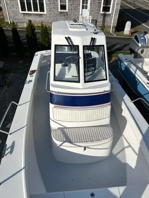Slide: The Image of 2015 Maritime Skiff 23 Patriot boat, white exterior, docked near a coastal building. - 2