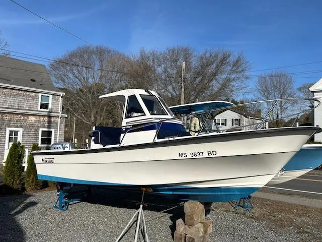 Slide: The Image of 2015 Maritime Skiff 23 Patriot boat on display outdoors, with blue trim and registration number visible. - 3