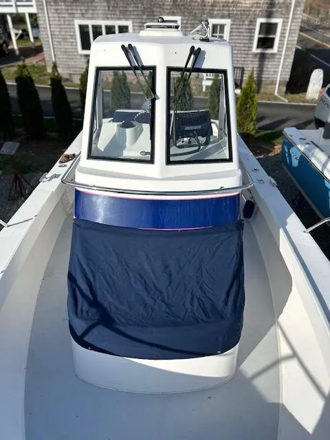Slide: The Image of 2015 Maritime Skiff 23 Patriot boat with blue cover, docked near wooden building. - 7