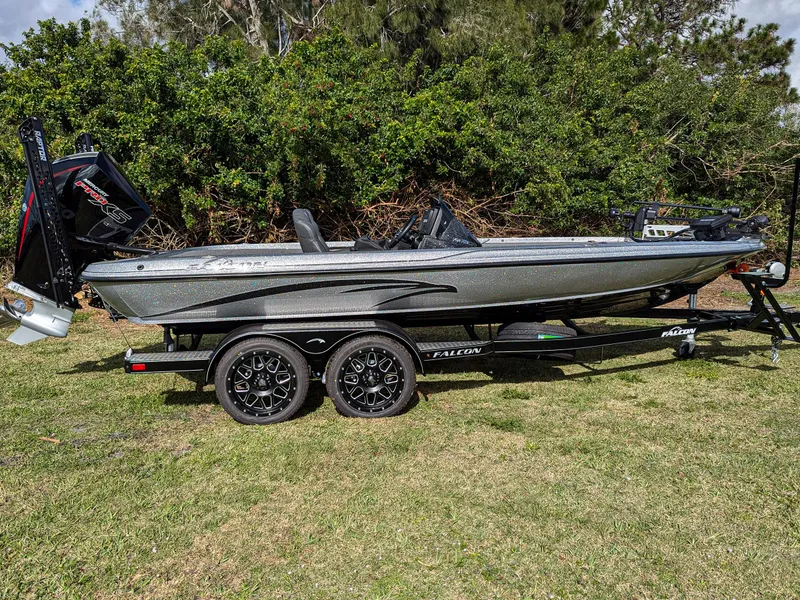 Slide: The Image of 2025 Falcon F20 PREDATOR boat on trailer, parked on grass with trees in background. - 1