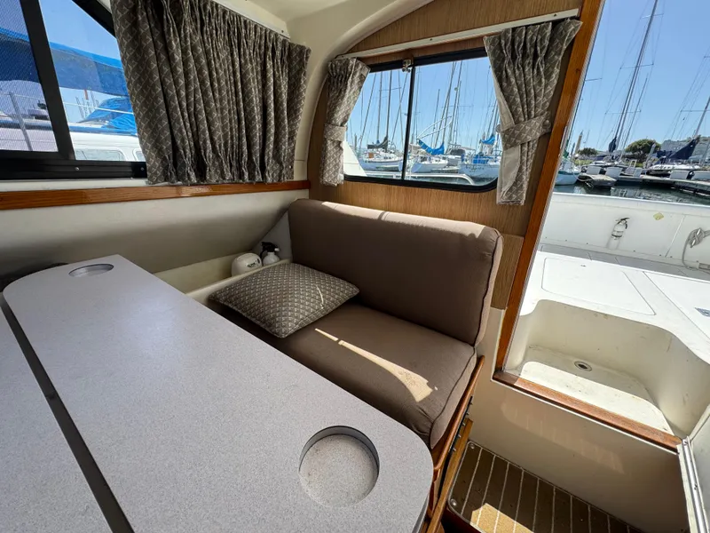 Slide: The Image of Interior of 1988 Bertram 28 Sport Fisherman with seating, table, and marina view. - 10