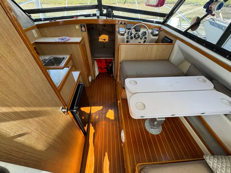 Slide: The Image of Interior of a 1988 Bertram 28 Sport Fisherman boat with wood flooring and compact seating area. - 13