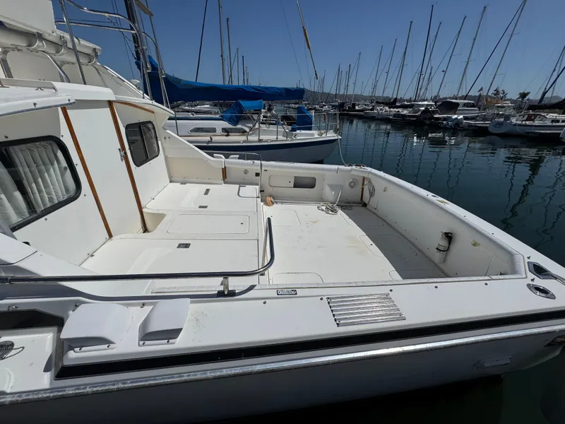 Slide: The Image of 1988 Bertram 28 Sport Fisherman boat docked in a marina, showcasing spacious deck area. - 19