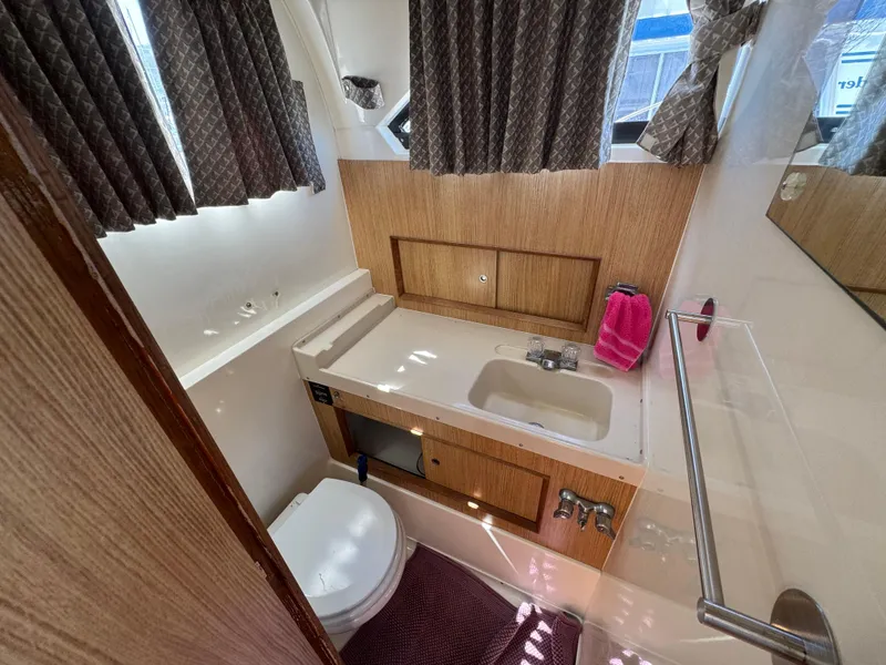 Slide: The Image of 1988 Bertram 28 Sport Fisherman bathroom with sink, toilet, and window curtains. - 9