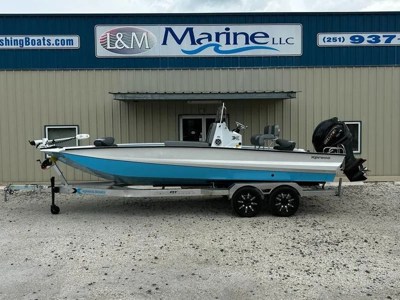 Slide: The Image of 2025 Xpress X23B Lounge boat on trailer outside L&M Marine LLC building. - 0