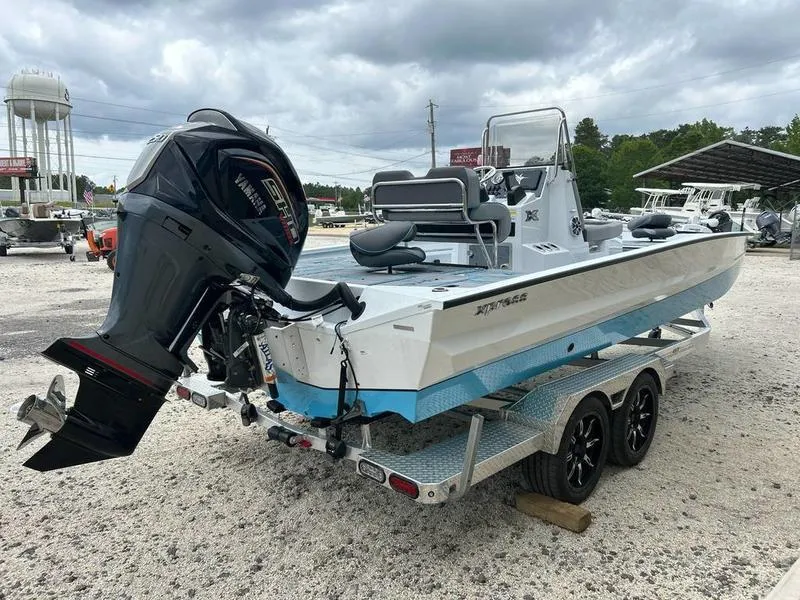 Slide: The Image of 2025 Xpress X23B Lounge boat on trailer, featuring powerful outboard motor, parked outdoors. - 2