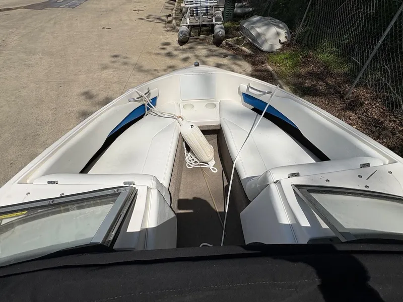 Slide: The Image of 2005 Regal 1800 Bowrider boat with white seating and blue accents, docked on concrete. - 4