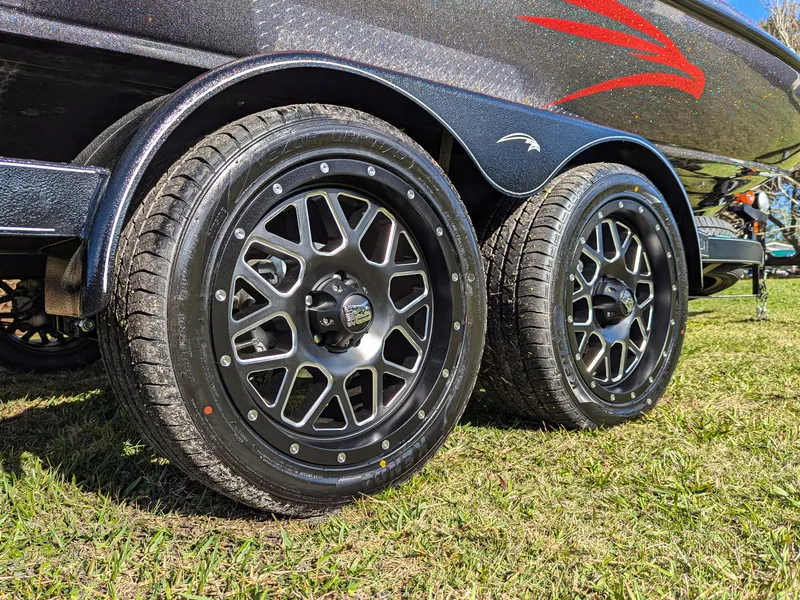 Slide: The Image of Trailer wheels of a 2025 Falcon F20 PREDATOR on grass, showcasing sleek black rims. - 8
