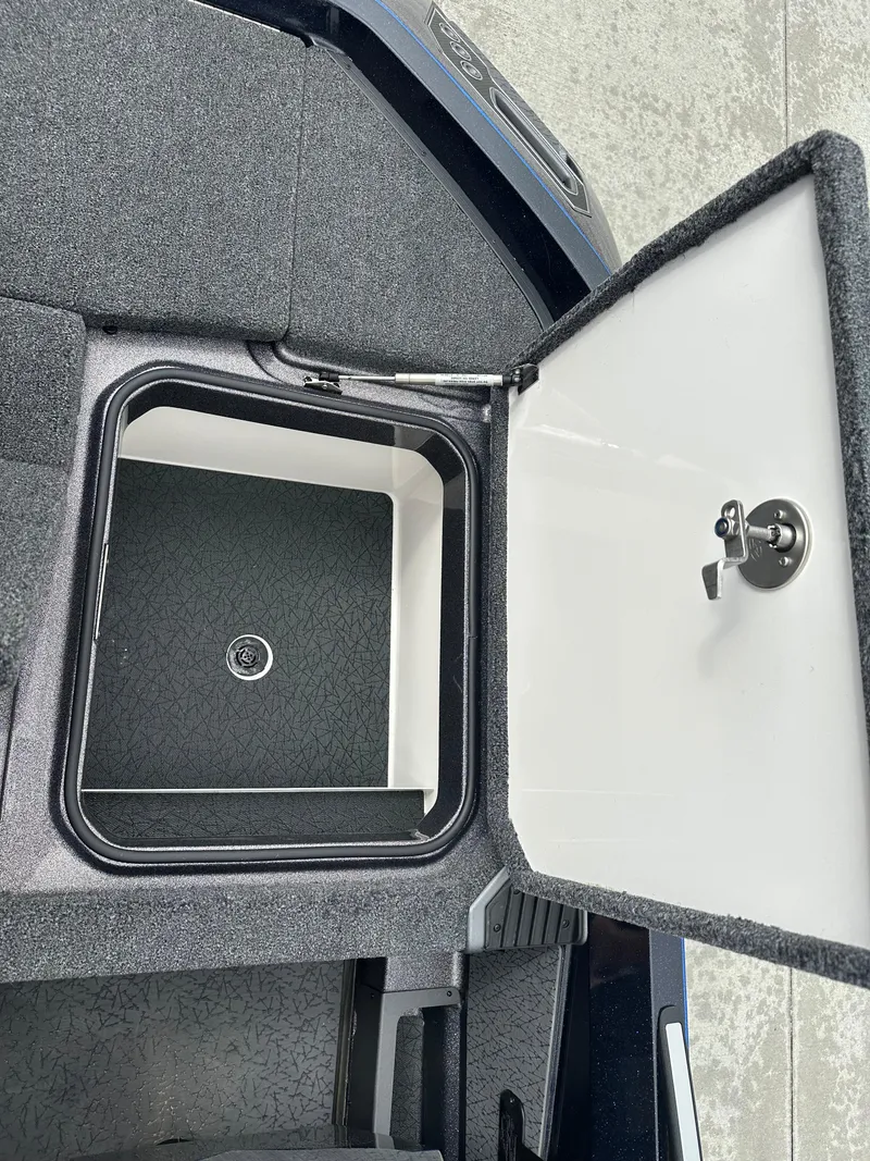 Slide: The Image of Open storage compartment in 2025 Vexus VXS21 boat, featuring secure latch and carpeted interior. - 26
