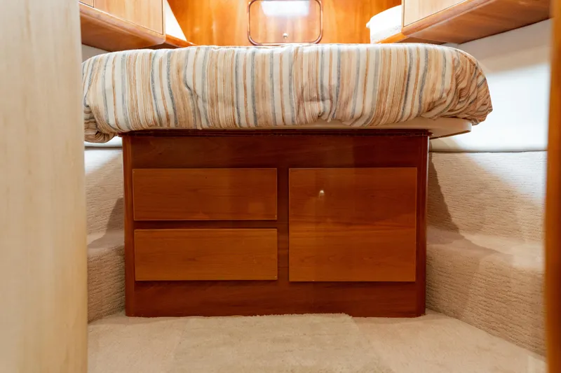 Slide: The Image of 2004 Ocean Yachts 50 Super Sport cabin with striped bedding and wooden storage drawers. - 46