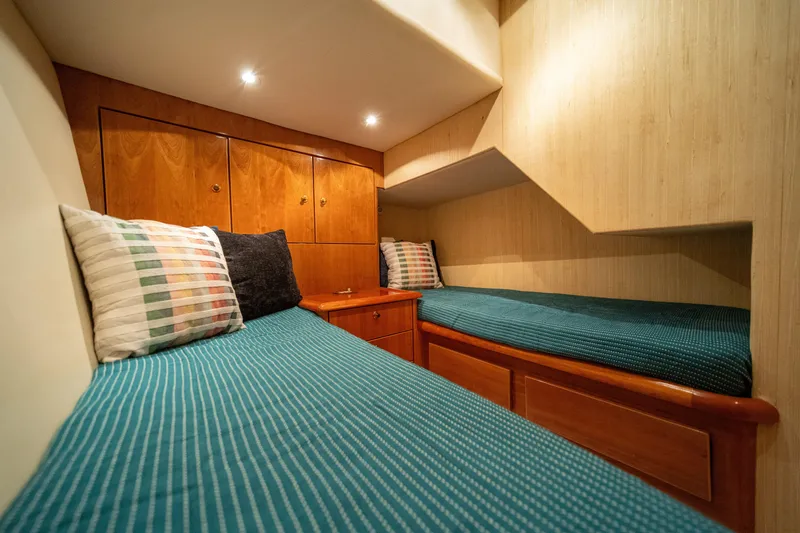 Slide: The Image of Cozy twin cabin in 2004 Ocean Yachts 50 Super Sport with wood accents and teal bedding. - 52