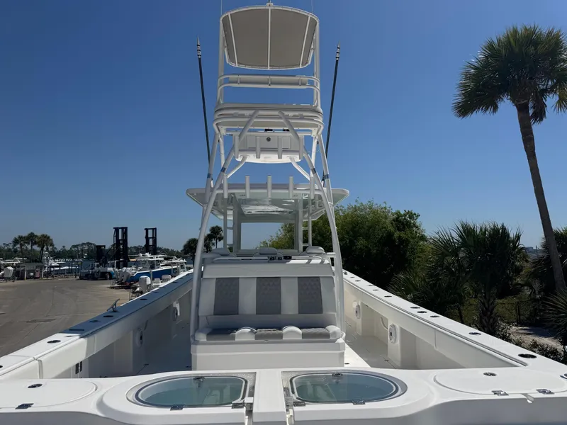 Slide: The Image of 2022 Invincible 46 Catamaran with tower, docked under clear blue sky, surrounded by palm trees. - 18