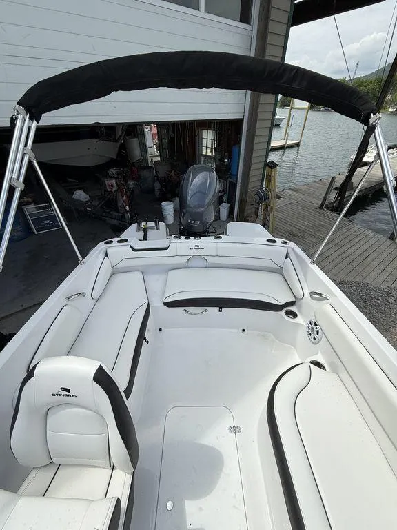 Slide: The Image of 2025 Stingray 182SC boat interior with white seating and black canopy, docked by the water. - 11