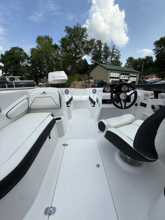 Slide: The Image of 2025 Stingray 182SC boat interior with white seating and steering wheel, under a cloudy sky. - 22