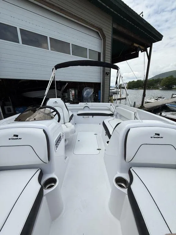 Slide: The Image of 2025 Stingray 182SC boat interior with seating, docked near a marina. - 24