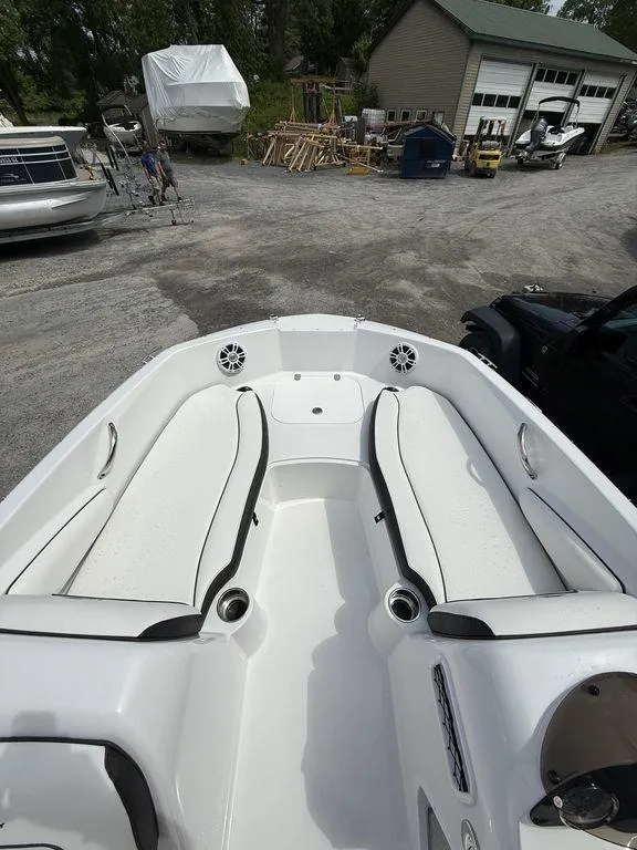 Slide: The Image of 2025 Stingray 182SC boat interior with white seating, parked in a boatyard. - 25