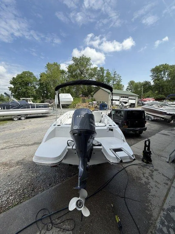 Slide: The Image of 2025 Stingray 182SC boat with outboard motor, parked outdoors under a partly cloudy sky. - 3