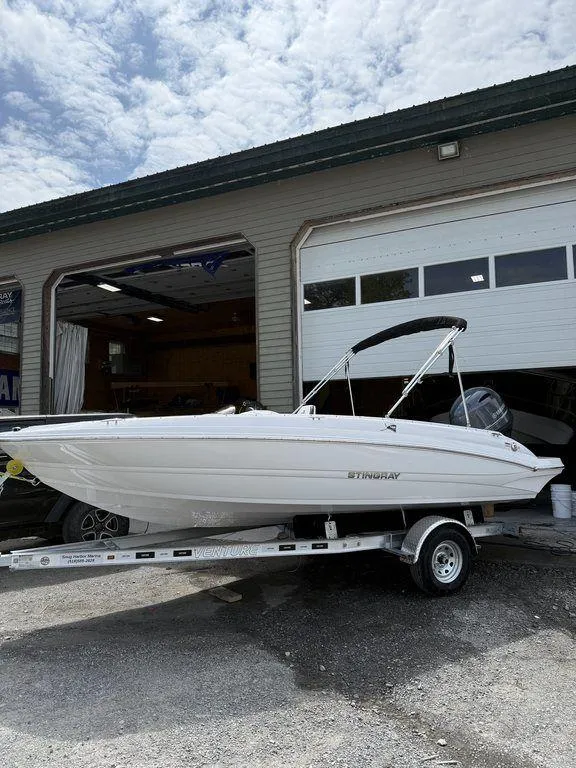 Slide: The Image of 2025 Stingray 182SC boat on trailer outside a garage under a cloudy sky. - 5