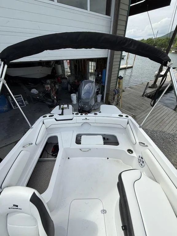 Slide: The Image of 2025 Stingray 182SC boat with spacious seating, docked near a boathouse. - 9