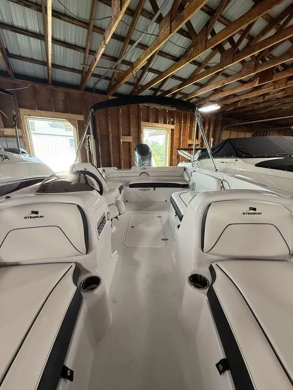 Slide: The Image of 2025 Stingray 182SC boat interior in a wooden boathouse, showcasing seating and steering area. - 25