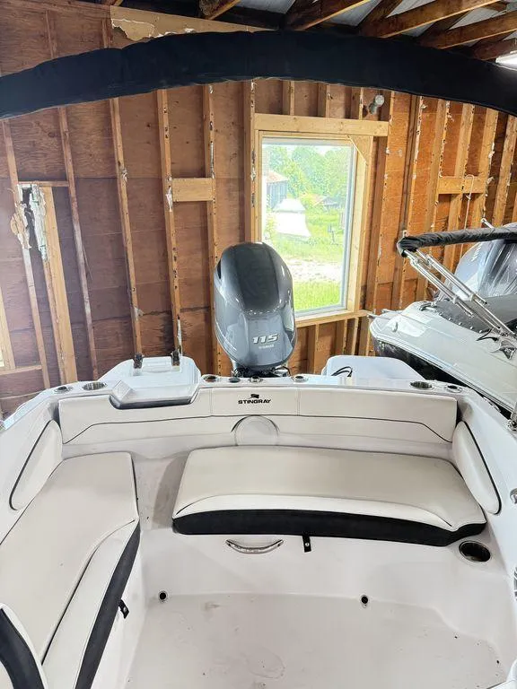 Slide: The Image of 2025 Stingray 182SC boat interior with seating and motor in a wooden garage. - 4