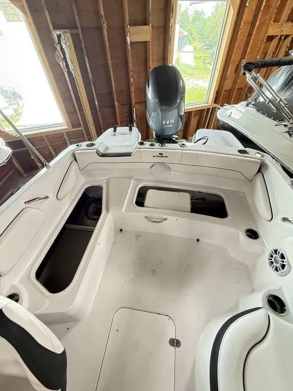 Slide: The Image of 2025 Stingray 182SC boat interior with seating and motor in a wooden boathouse. - 8
