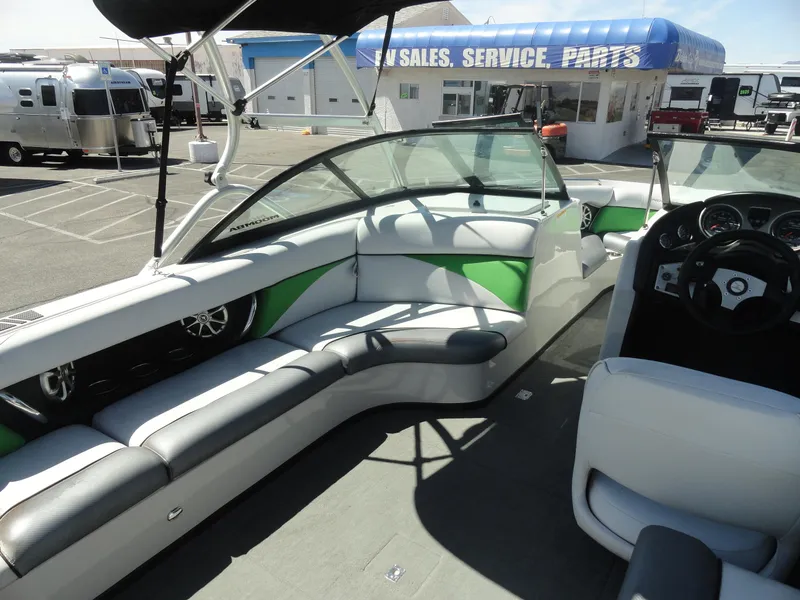 Slide: The Image of 2011 Moomba Outback V boat interior with green and white seating, parked near sales and service center. - 14