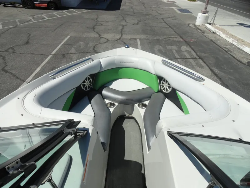 Slide: The Image of 2011 Moomba Outback V boat interior with green and white seating, parked on asphalt. - 16