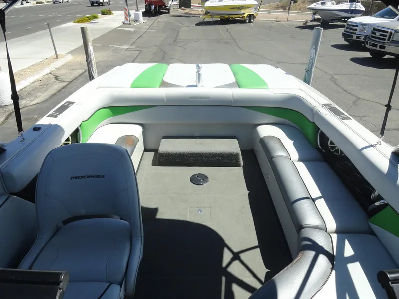 Slide: The Image of 2011 Moomba Outback V boat interior with green and white seating, parked outdoors. - 17