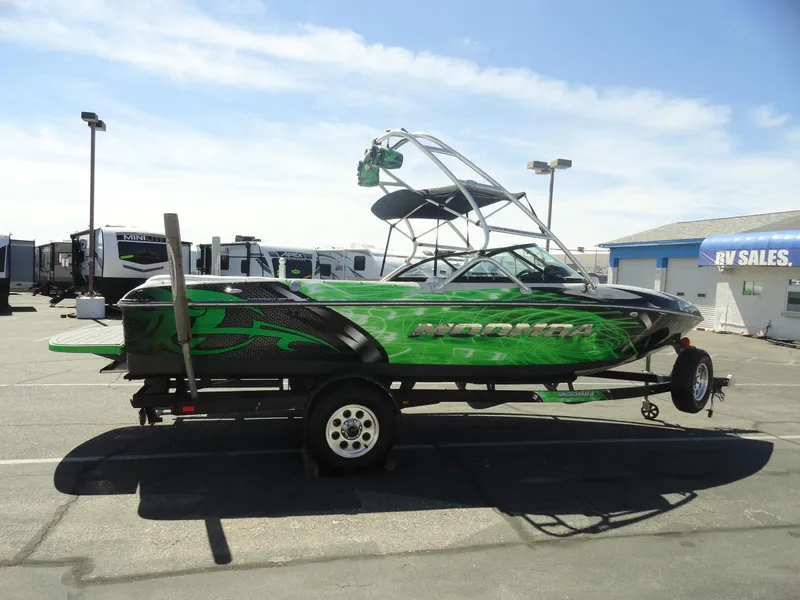 Slide: The Image of 2011 Moomba Outback V boat with vibrant green design on trailer in parking lot. - 5
