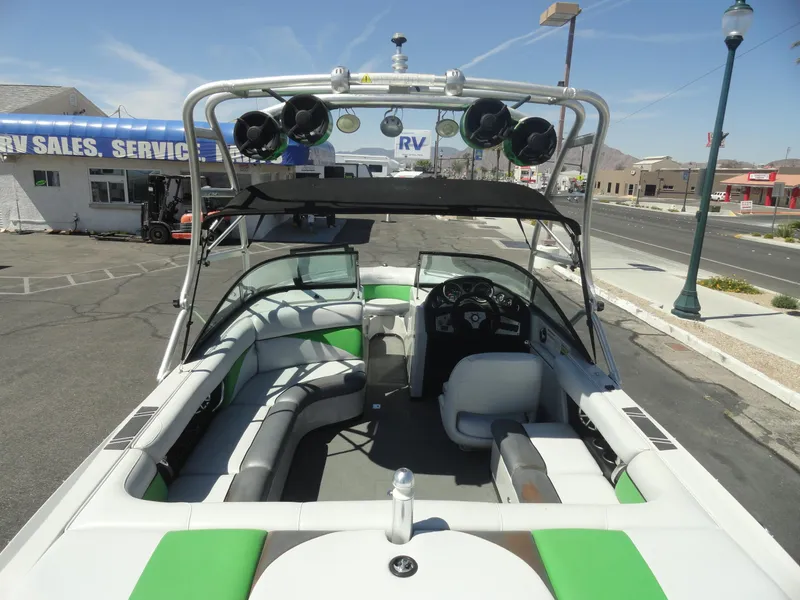Slide: The Image of 2011 Moomba Outback V boat with green and white interior, parked near RV sales. - 6