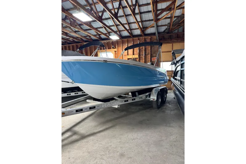 The Image of 2025 Stingray 172 SC boat in storage, blue hull, on trailer, indoor warehouse setting. - 0