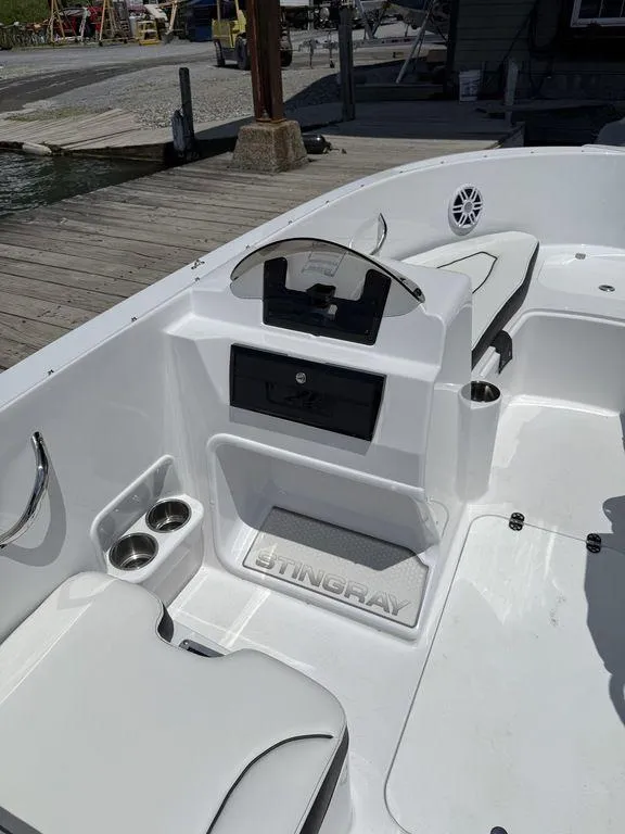 Slide: The Image of 2025 Stingray 172SC boat interior with seating and cup holders at a dock. - 14