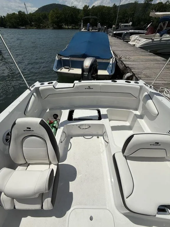 Slide: The Image of 2025 Stingray 172SC boat interior at dock, featuring white seating and scenic lake view. - 19