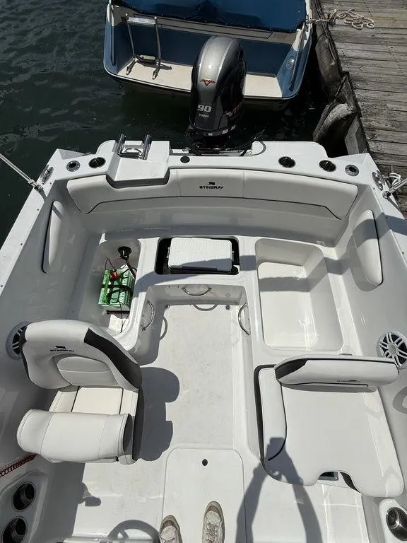 Slide: The Image of 2025 Stingray 172SC boat interior with seating and motor, docked by the water. - 21