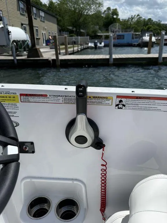 Slide: The Image of Control panel of a 2025 Stingray 172SC boat docked by the water. - 27
