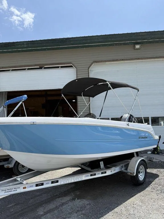 Slide: The Image of 2025 Stingray 172SC boat with blue hull on trailer, parked outside a garage. - 35
